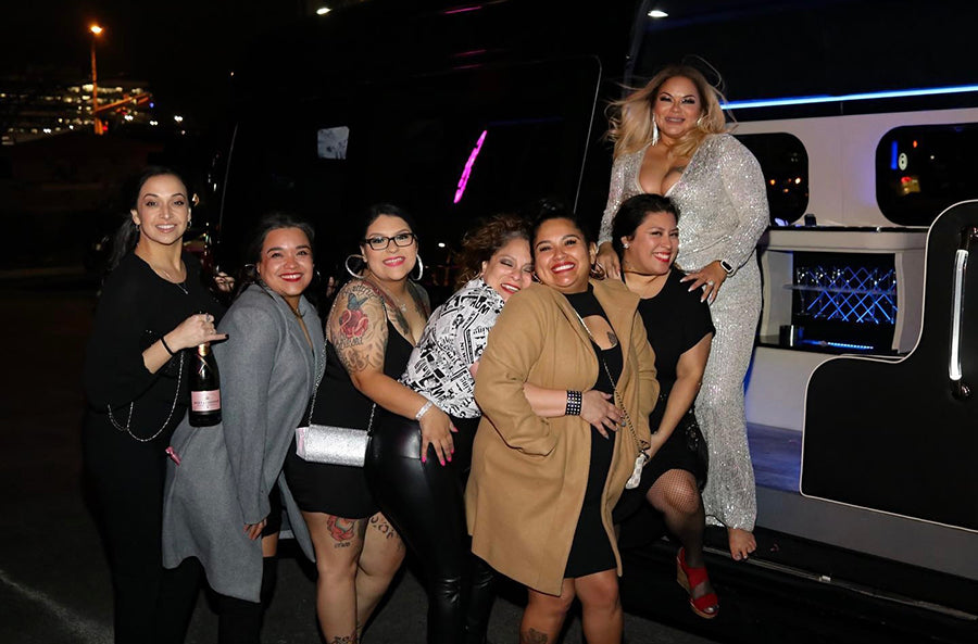Group of women posing in front of a luxury sprinter van limousine at night in Austin Texas