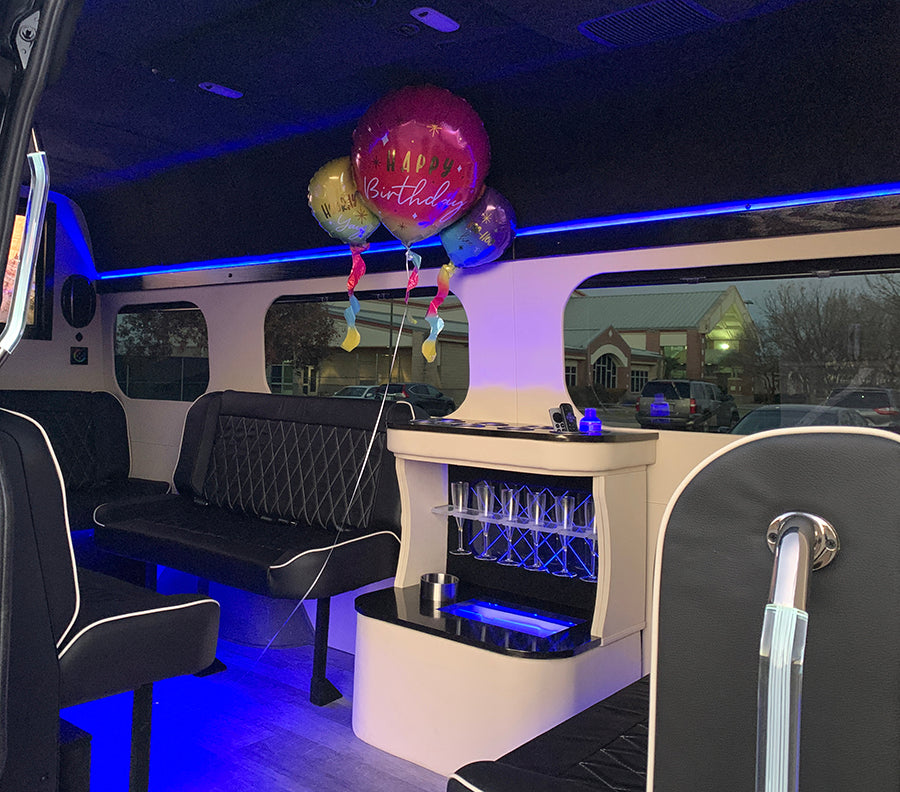 Interior of a luxury sprinter van party bus limo with black leather seats, a bar area, and balloons for birthdays in Austin Texas